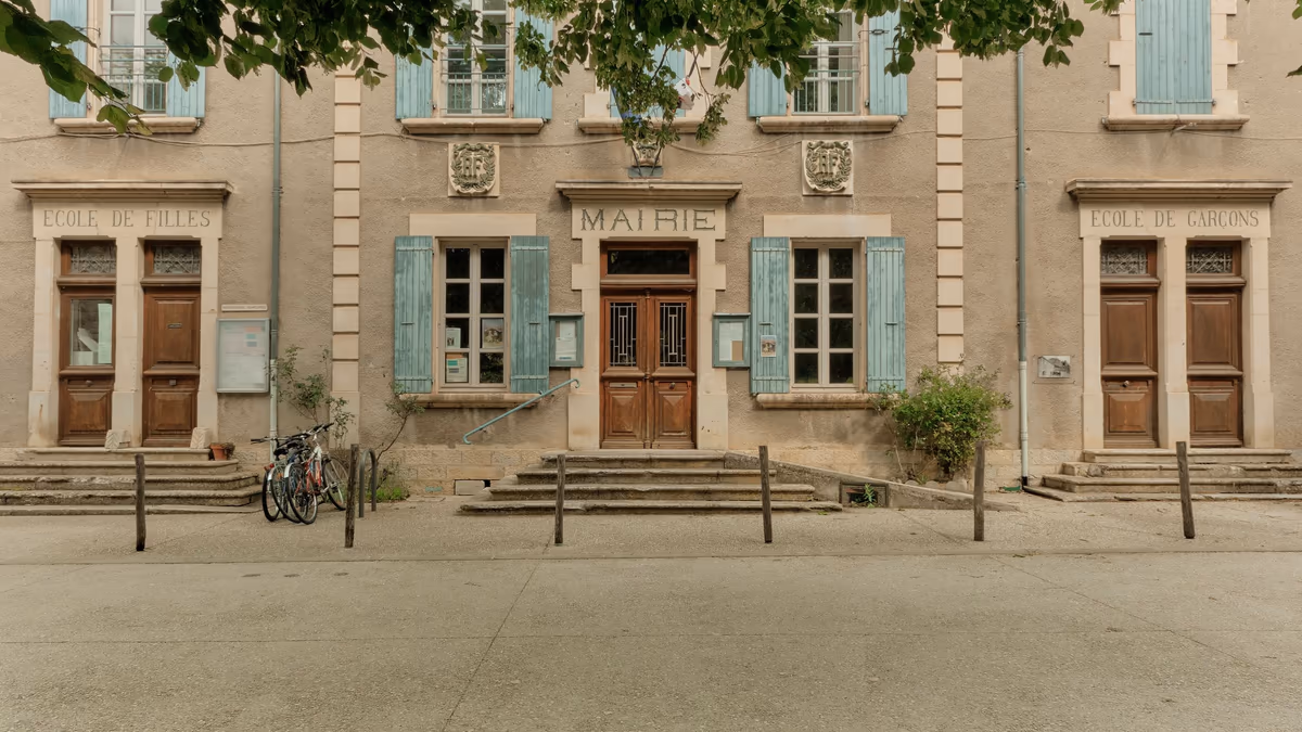 Façade d'une mairie de village française, l'enseigne MAIRIE au-dessus de la porte centrale encadrée par les frontons École de filles et École de garçons