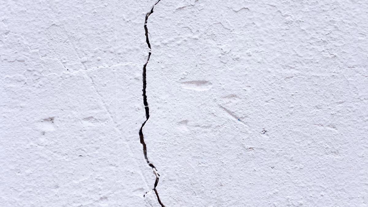 Fissure verticale ouverte sur un mur de façade enduit d'une maison individuelle