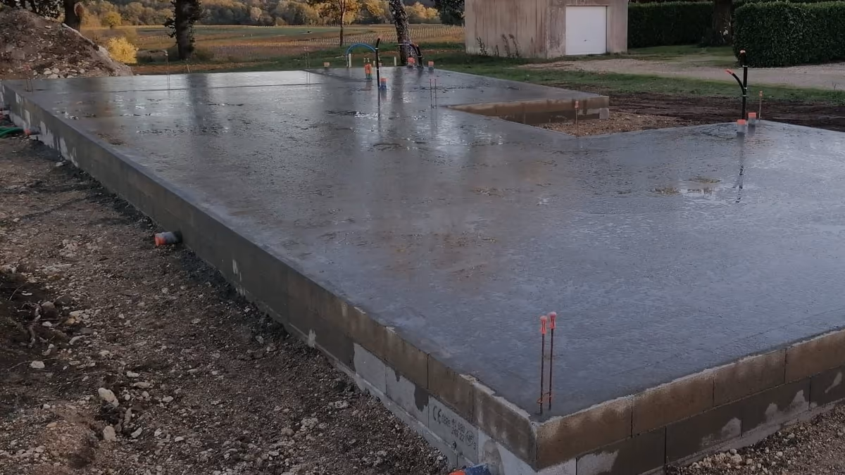 Dalle béton fraîchement coulée sur un soubassement en blocs béton, attentes de réseaux en place, pour une maison individuelle neuve
