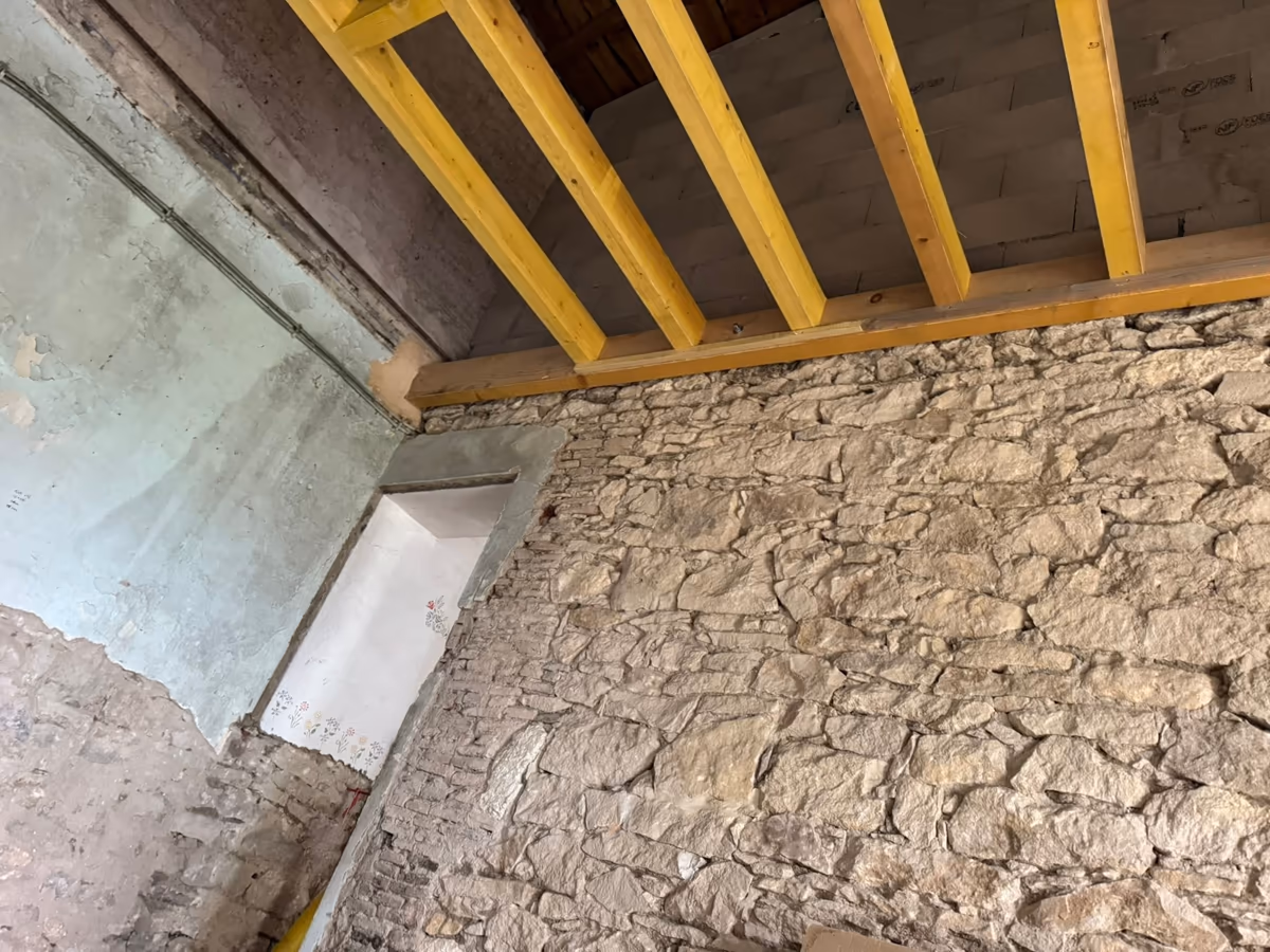 Solives de plancher en bois neuf reposant sur une pièce d'appui posée en tête d'un mur ancien en moellons de pierre